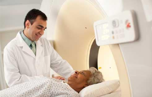 Doctor stands with patient entering a low dose CT