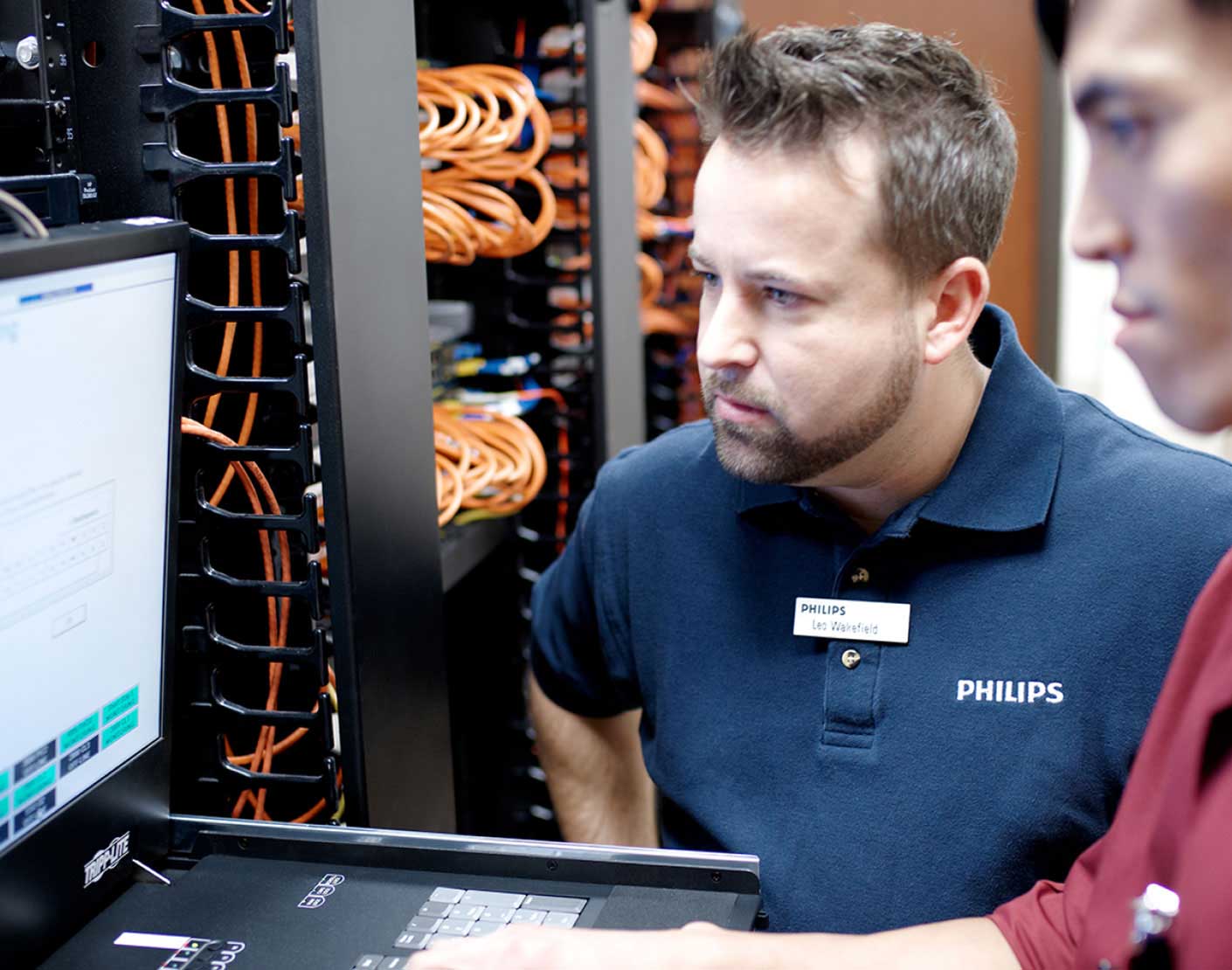 Two men look at a screen in a server room