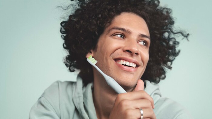 Man holds tooth brush while smiling.