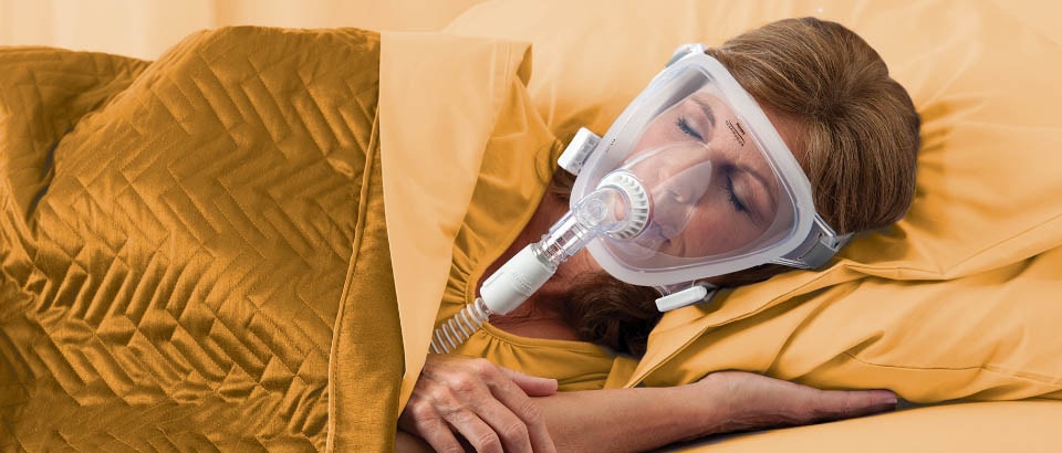 Woman wearing yellow, sleeping with a mask covering her face