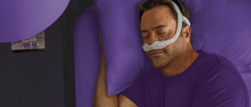Man wearing a purple t-shirt sleeping in a mask   