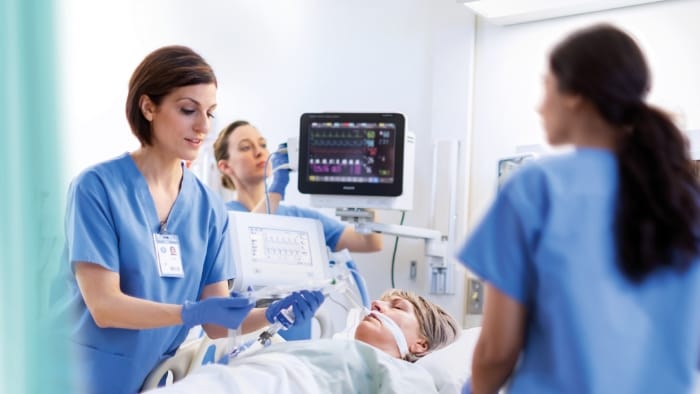 Image of three healthcare providers helping a patient