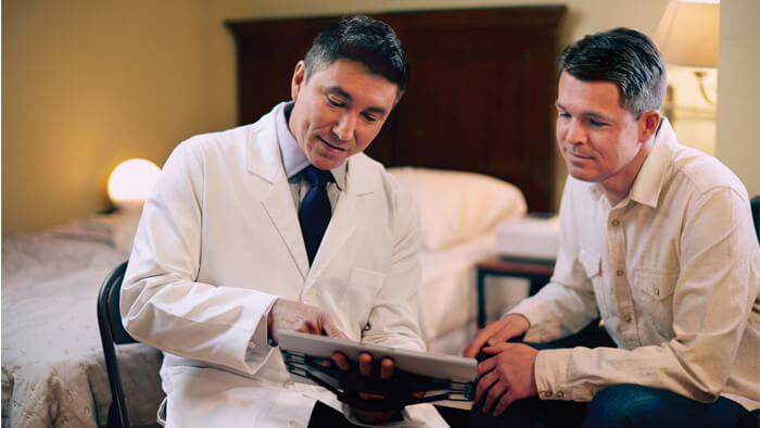 Photograph of doctor showing man results on tablet