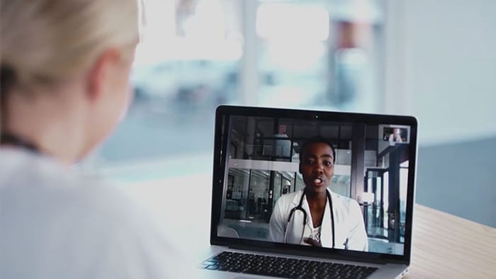 Healthcare worker speaking to patient on laptop