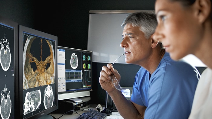 Health professionals analyzing scans on monitor