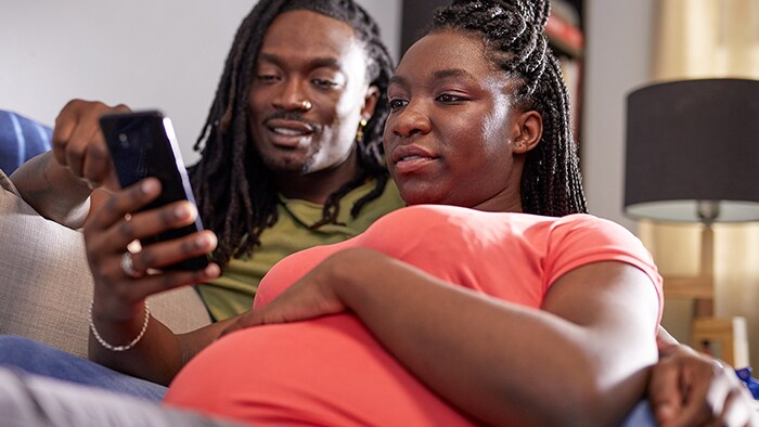 Pregnant woman with husband viewing app on phone