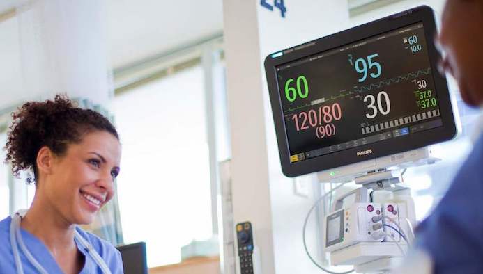 Two doctors smiling with monitor between them