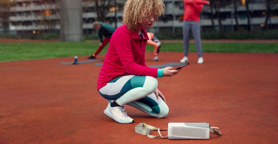 Woman connecting to her Philips bluetooth speaker outdoors