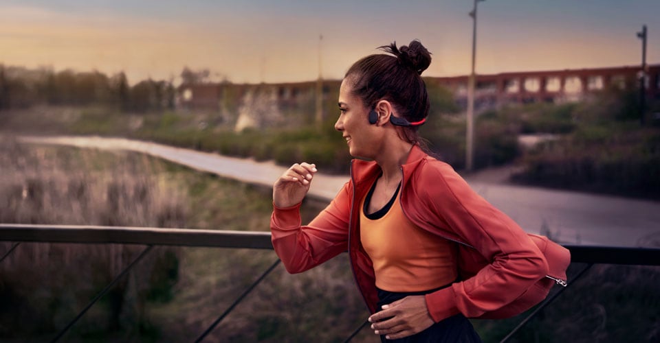Athlete using bone conduction headphones on a run outside
