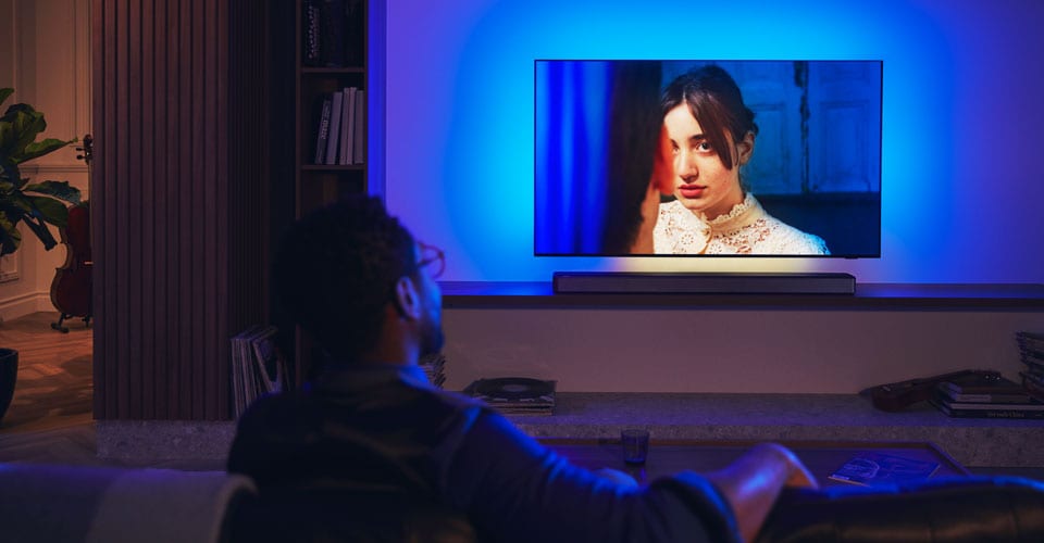Man enjoying philips Ambilight TV with soundbar