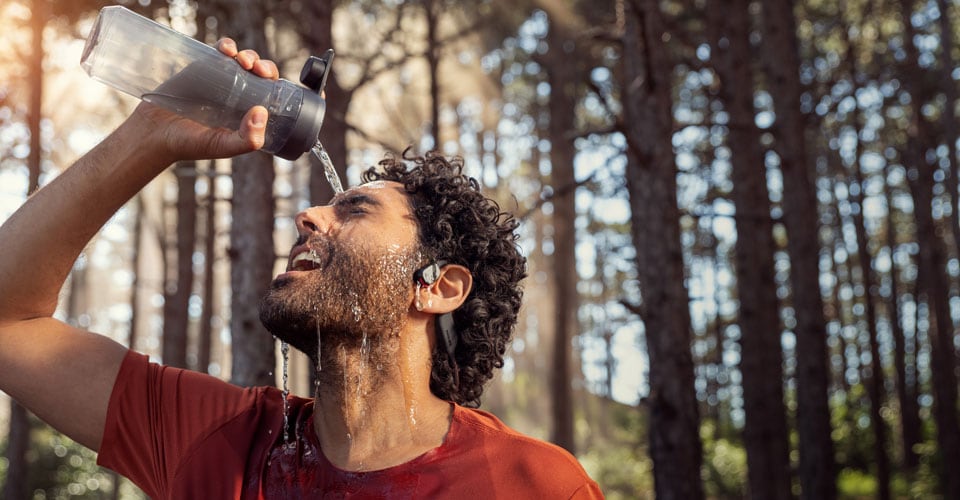 Athlete pouring water over waterproof open ear headphones