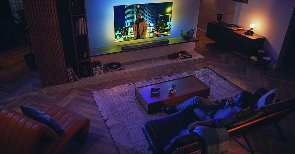 Man enjoying his Philips Ambilight TV with soundbar