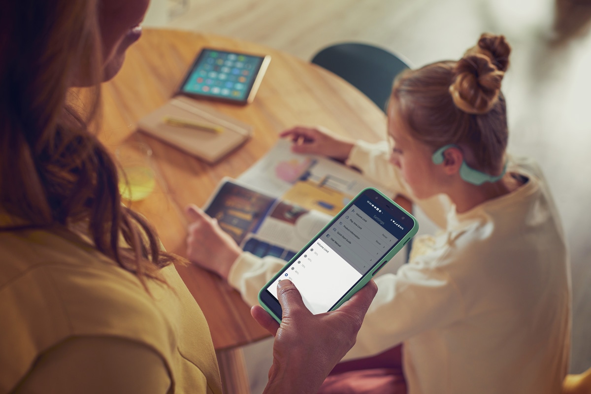 A parent using Philips Headphones app to control Kids Headphones volume