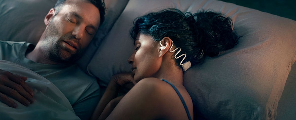 Couple sleeping, with the woman wearing Philips Sleep Headphones