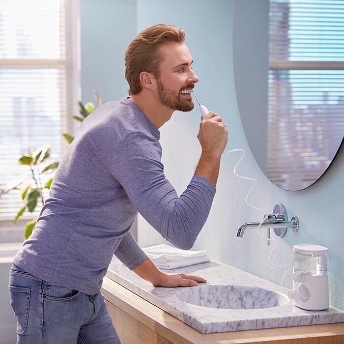 Man using power flosser in mirror