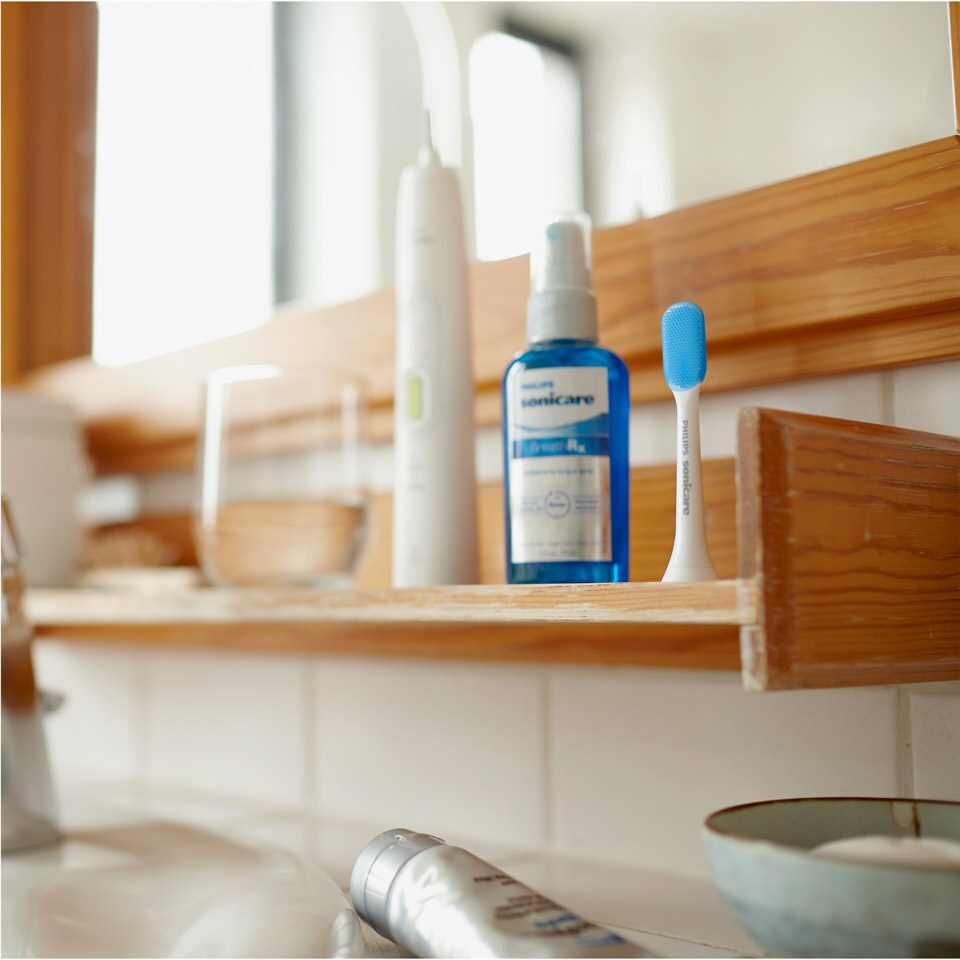 Philips Sonicare power toothbrush handle, BreathRx spray, and TongueCare+ brush head arranged on a counter