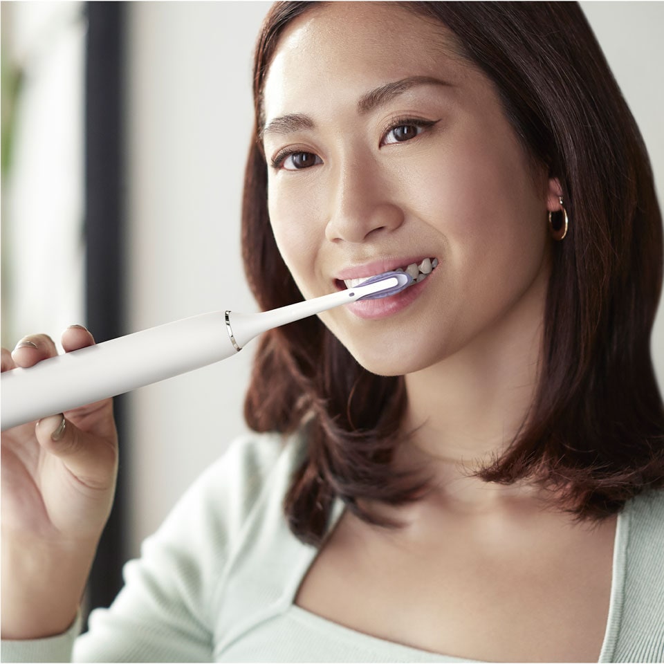 Man using a DiamondClean Smart with Premium Plaque Control brush head looking in a mirror