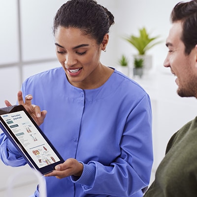 A dental professional showing a patient a chairside guide on a tablet