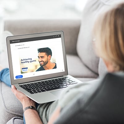 A patient reading an email about gingivitis on their laptop