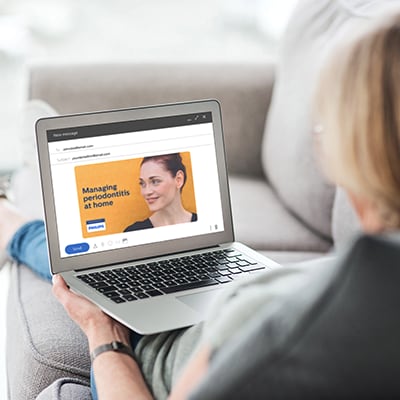 A patient reading an email about periodontitis on their laptop