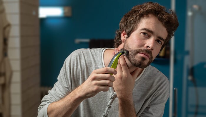 Young man with stylish hairstyle sitting and getting his beard shaved by  guy in black protective mask in barber shop 15291419 Stock Photo at Vecteezy